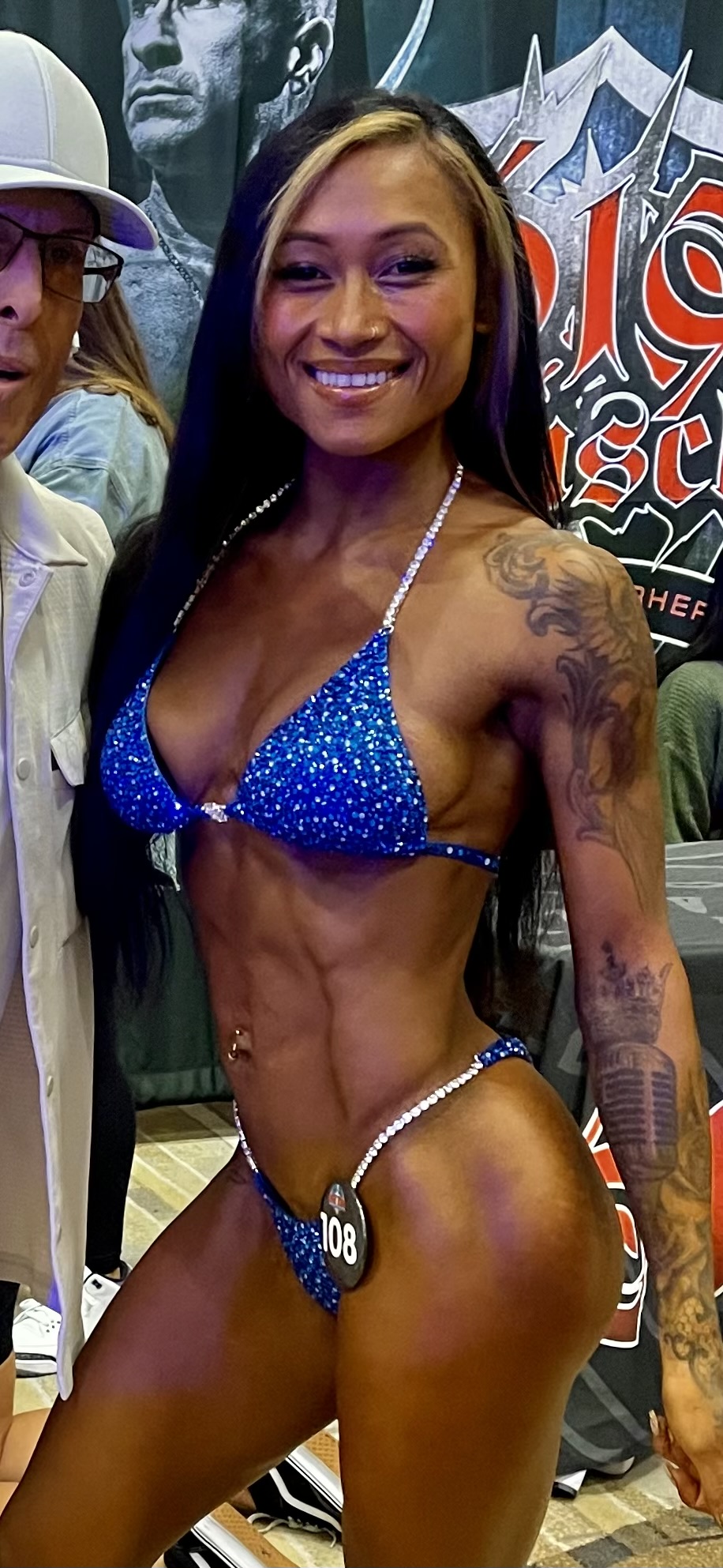 Selected female physique competitor wearing a blue competition suit